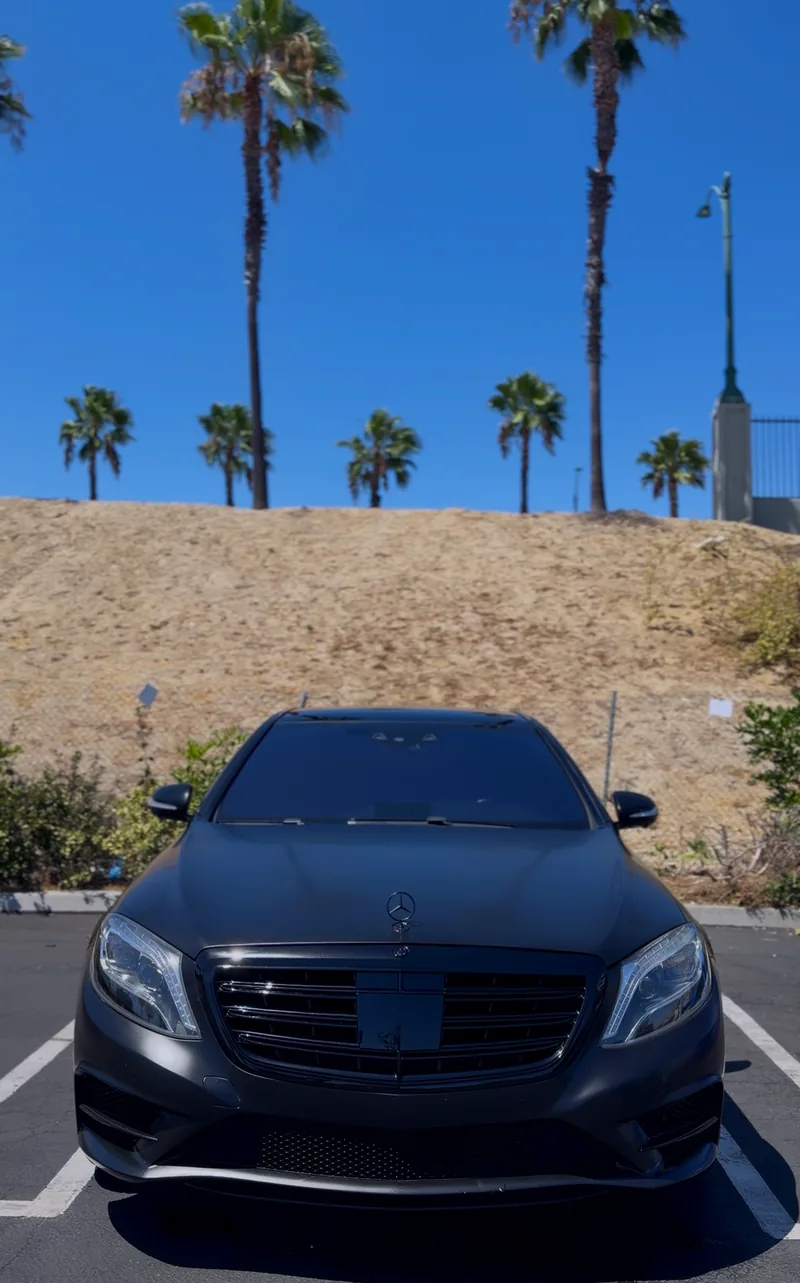 A satin grey Mercedes S63 parked under palm trees after a polish.