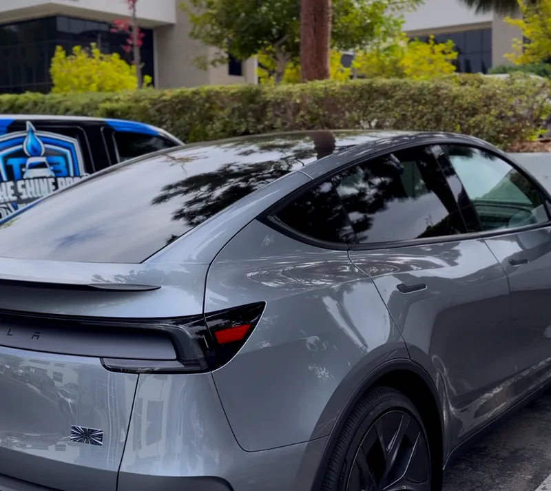A silver Tesla Model Y after a maintenance wash, with The Shine Bros van parked behind it.